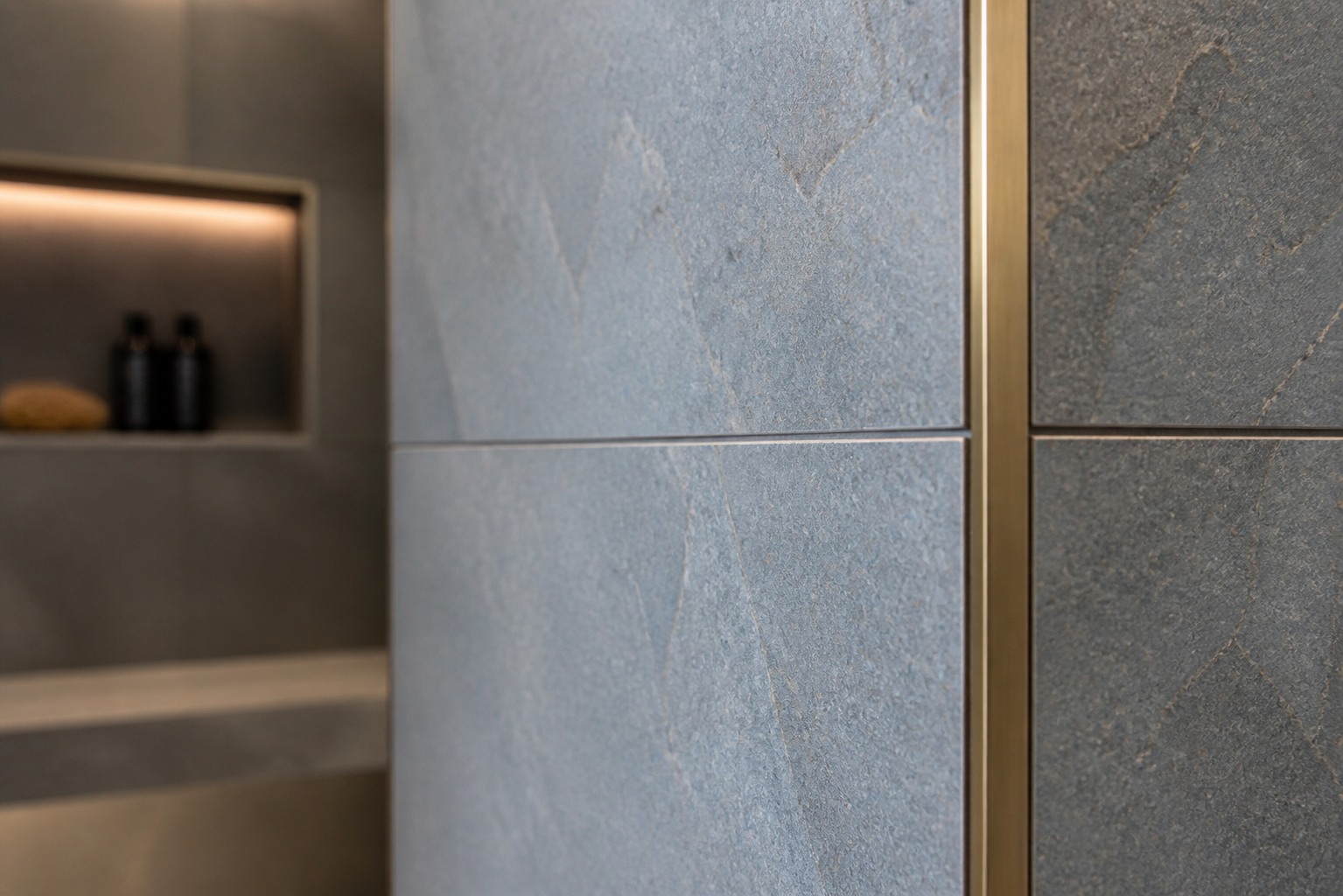 Blue-grey porcelain outside corner with bronze trim and aligned grout joint