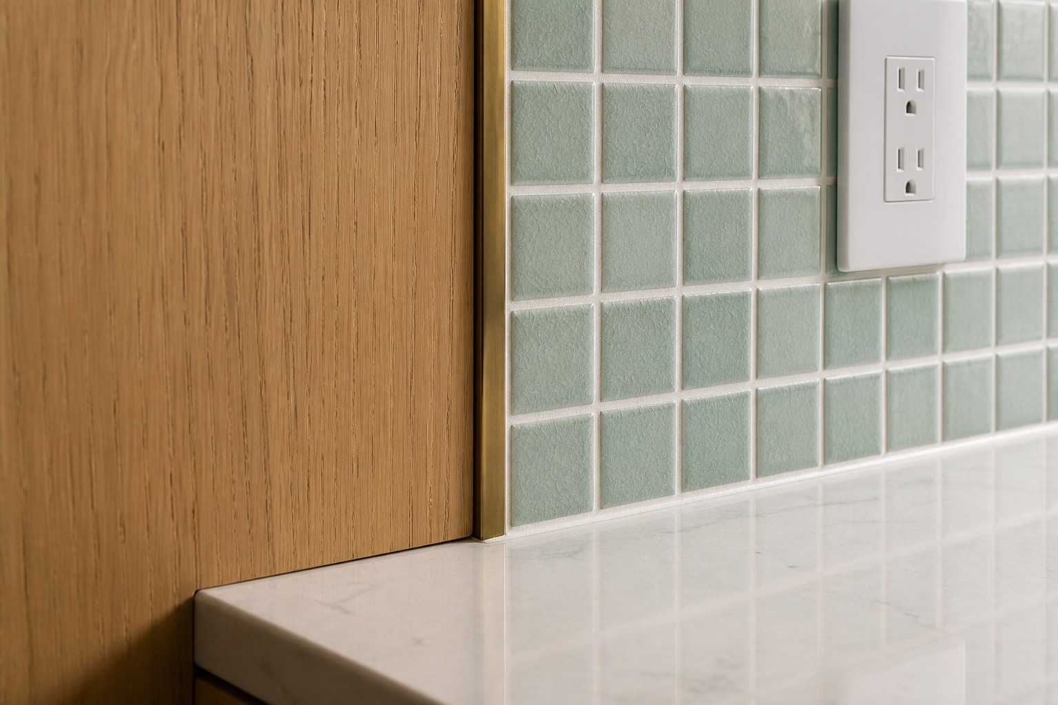 Celadon-green mosaic backsplash meeting oak cabinetry and pale quartz