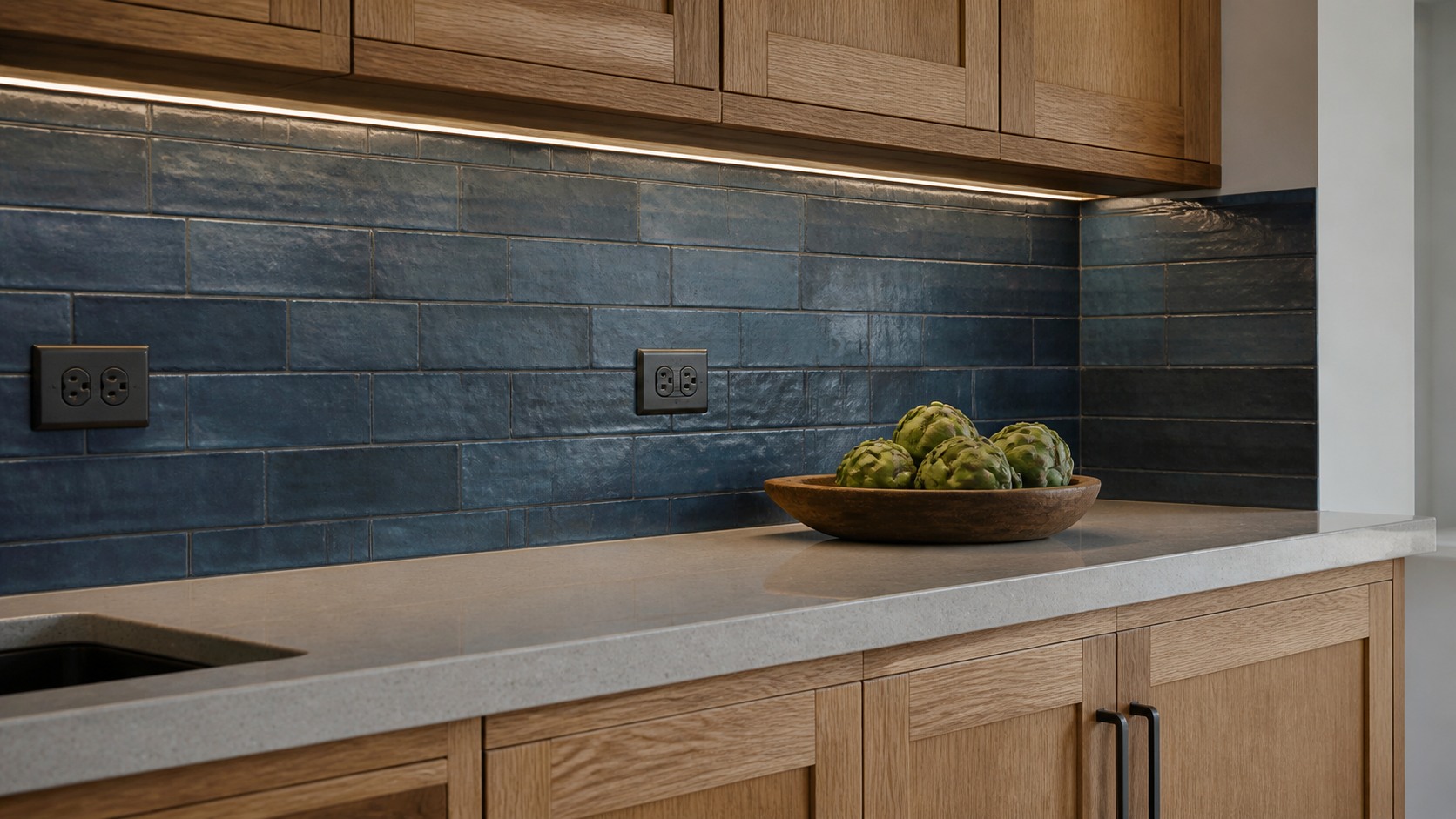 Handmade blue tile backsplash design with warm oak cabinetry and a stone counter