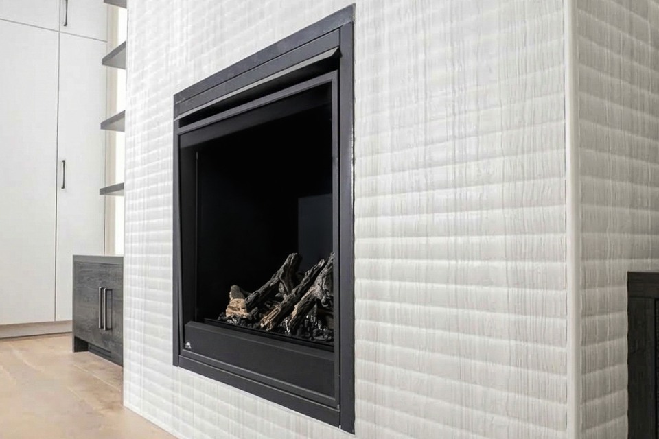 Close view of white textured fireplace tile wrapping an outside corner beside a black firebox