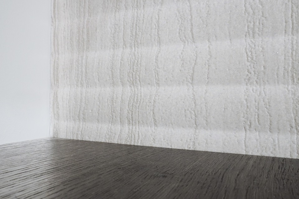 Close view of pale vertically veined fireplace tile meeting a dark wood shelf