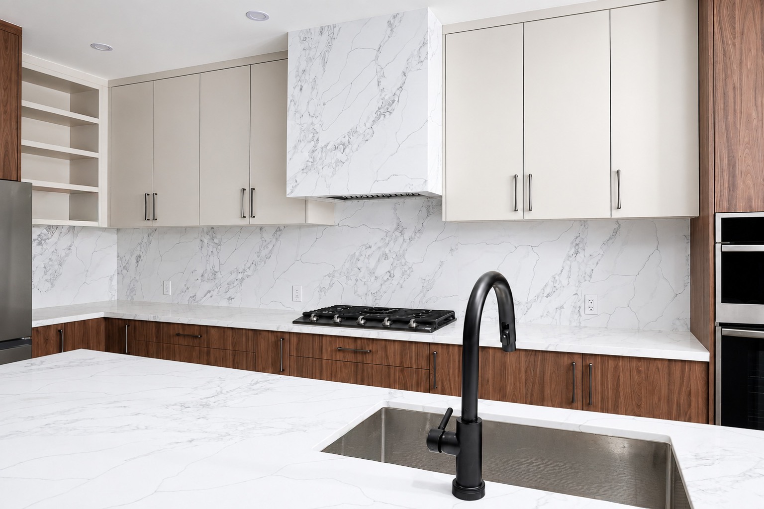 White marble-look kitchen backsplash and island beside white upper cabinets and wood lower cabinets
