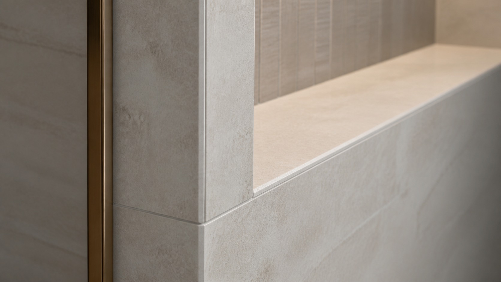 Close tile detail showing a mitred stone edge, niche return and fine grout joint